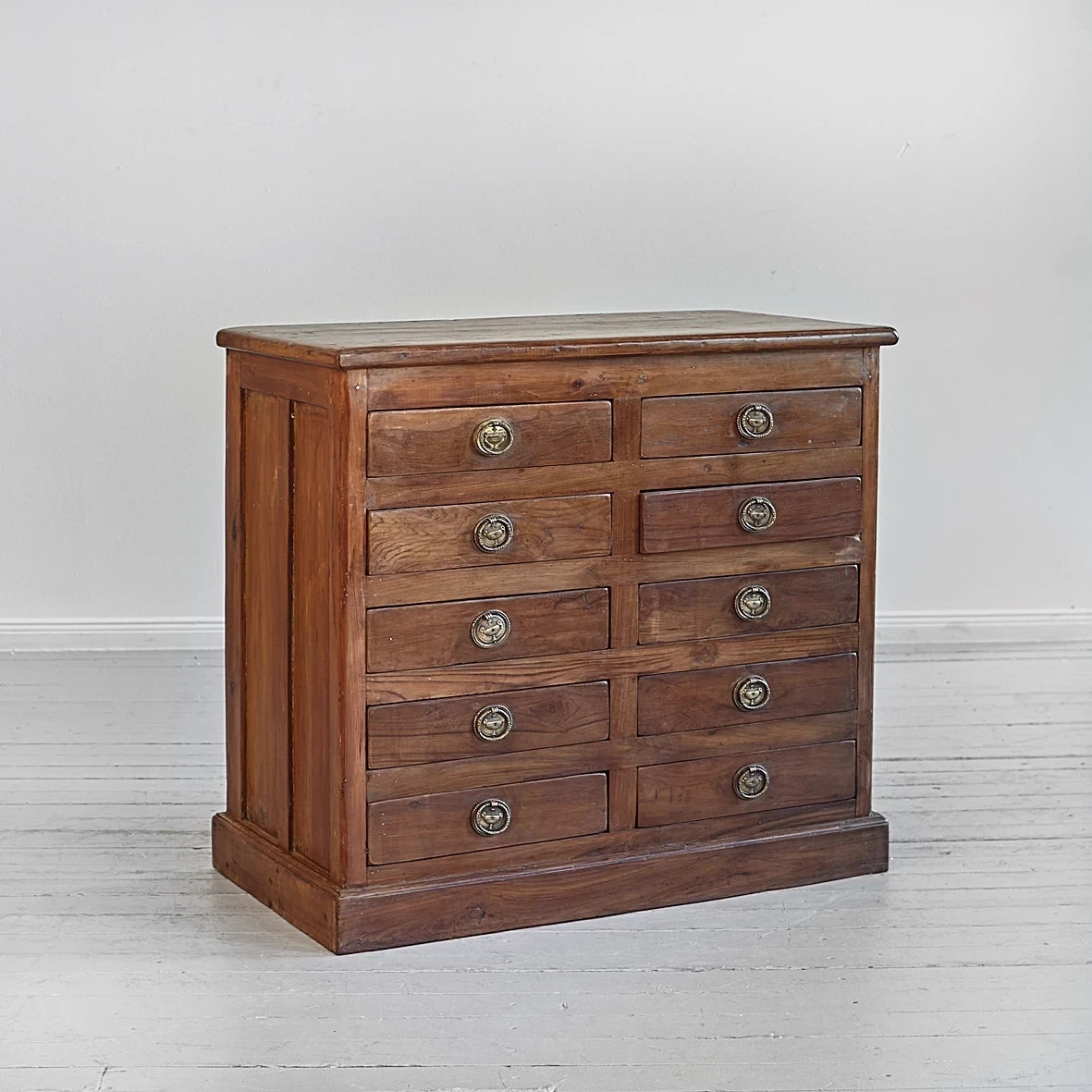 Wooden dresser with multiple drawers on a light gray background