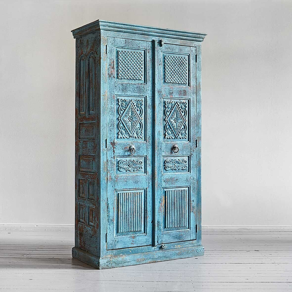 Vintage-style blue cabinet with intricate carvings on a white background