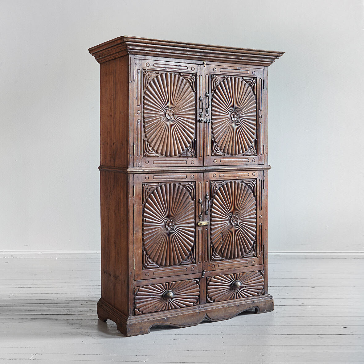 Wooden cabinet with decorative sunburst patterns on a white background