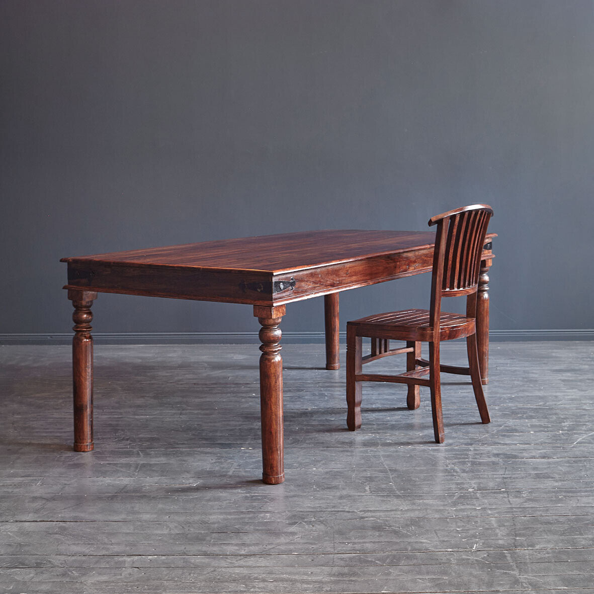 Wooden dining table with chair against a gray wall