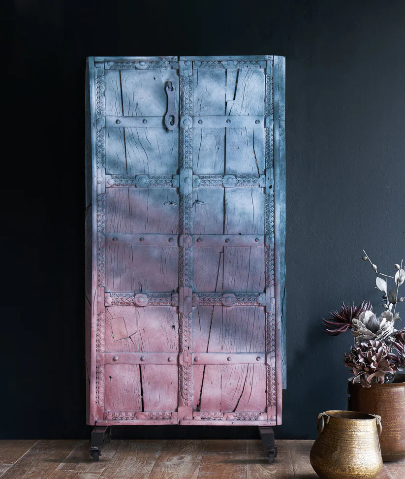 Rajasthani wooden door with iron stand, distressed blue and pink finish, 76 × 158 cm.

Handcrafted solid wood Rajasthani door panel with carved border and castor base.

Tall antique-style Indian door decor in blue and pink, made in India.