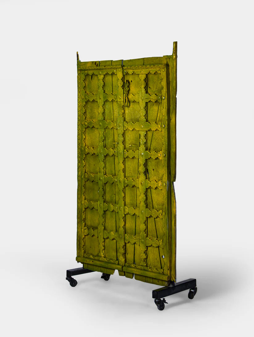 Unique Marwari wooden door with iron stand, distressed olive green finish, 94 × 171 cm.

Handcrafted solid wood Marwari door panel with grid pattern and castor base.

Tall antique-style Indian door decor in olive green, made in India.