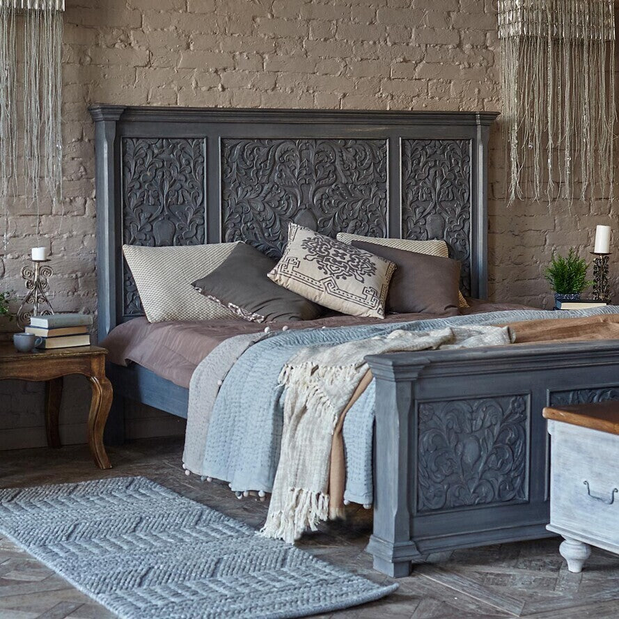Decorative bedroom with ornate headboard and matching furniture against a brick wall.
