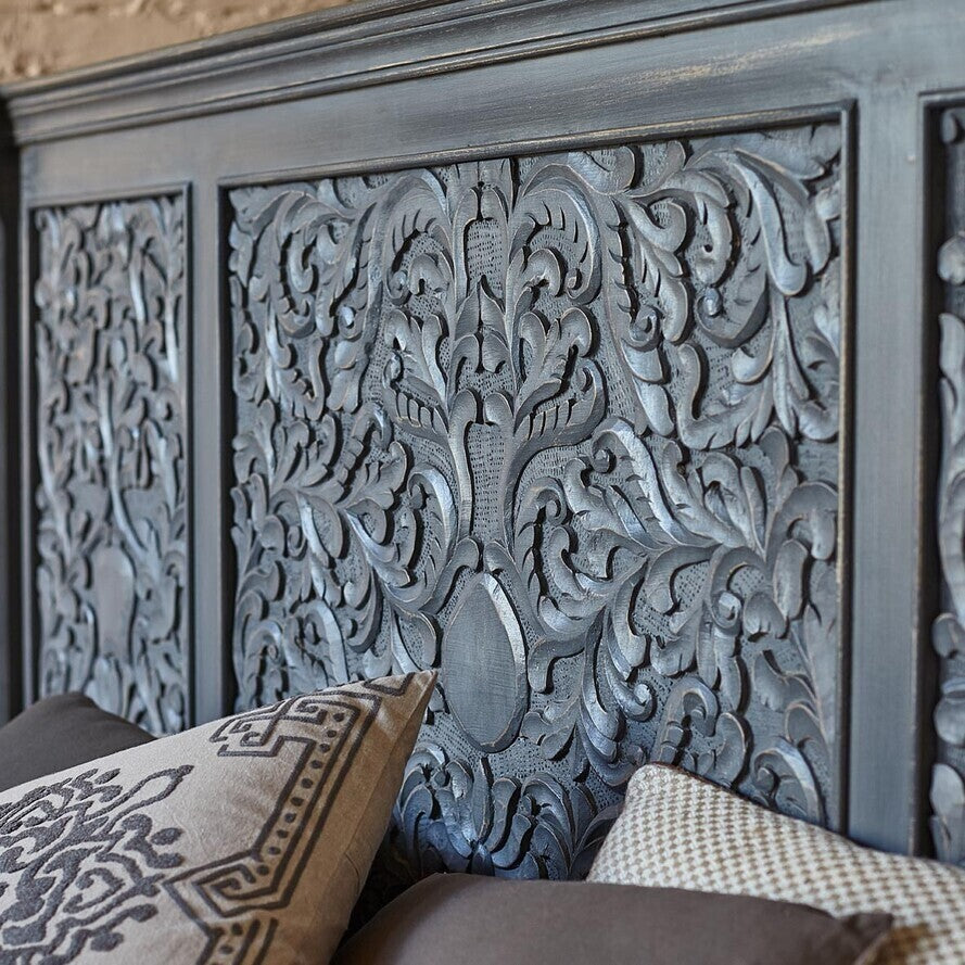 Decorative headboard with intricate carvings and patterned pillows.