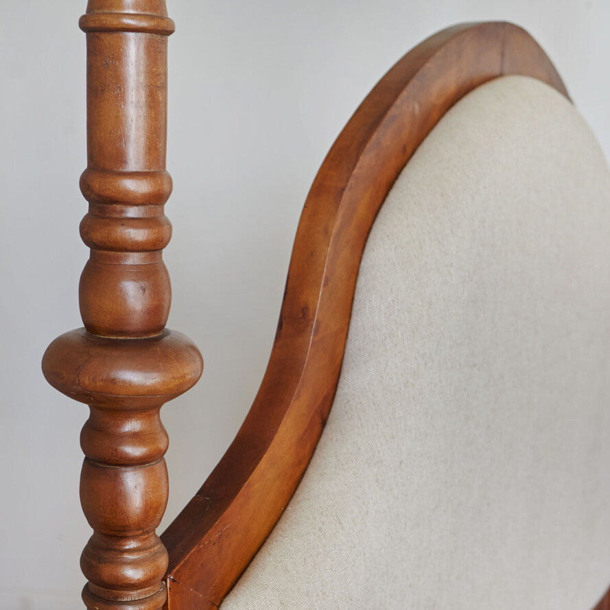Close-up of a wooden chair with a white cushioned seat against a plain background