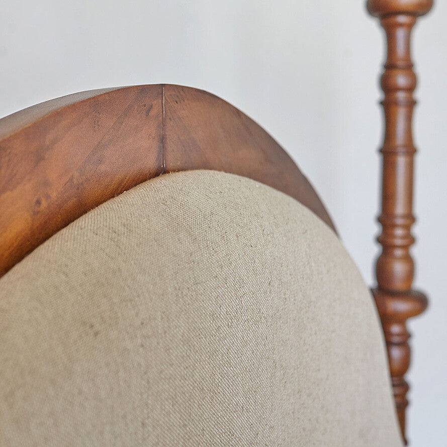 Close-up of a chair with wooden backrest and beige cushion on a plain background
