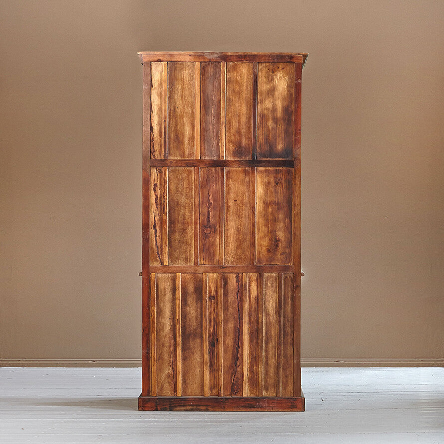 Wooden cabinet with a rustic design against a plain wall.