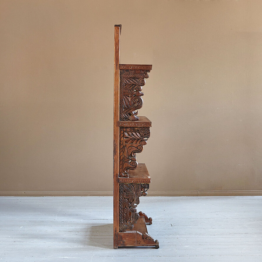 Carved wooden shelf against a beige wall