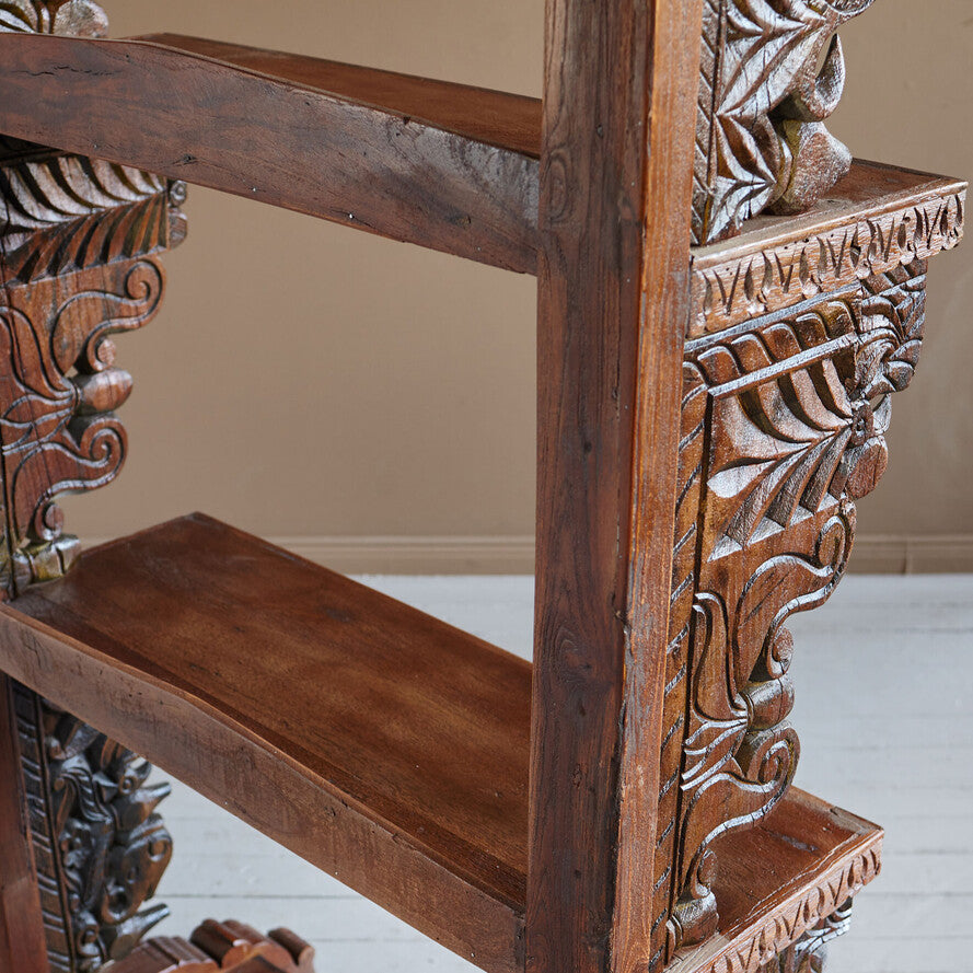 Close-up of a wooden chair with intricate carvings on a neutral background