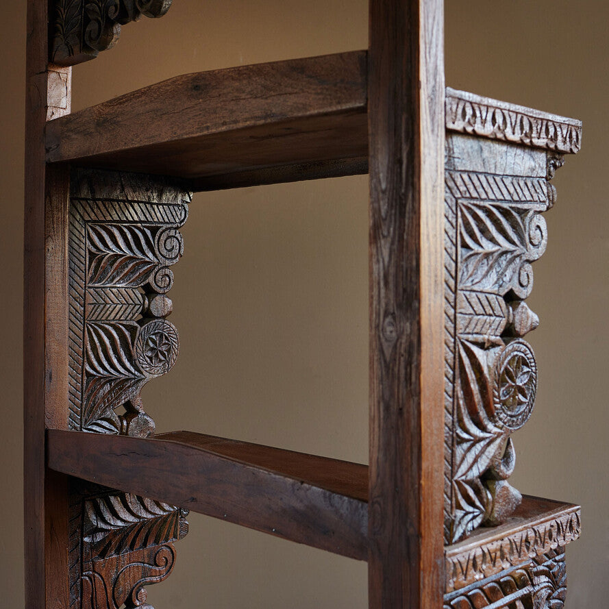 Carved wooden shelf with intricate patterns on a plain background