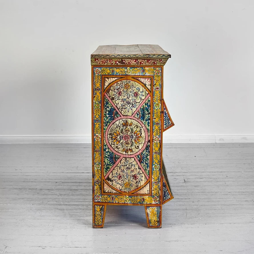 Decorative side table with floral patterns on a white floor and wall