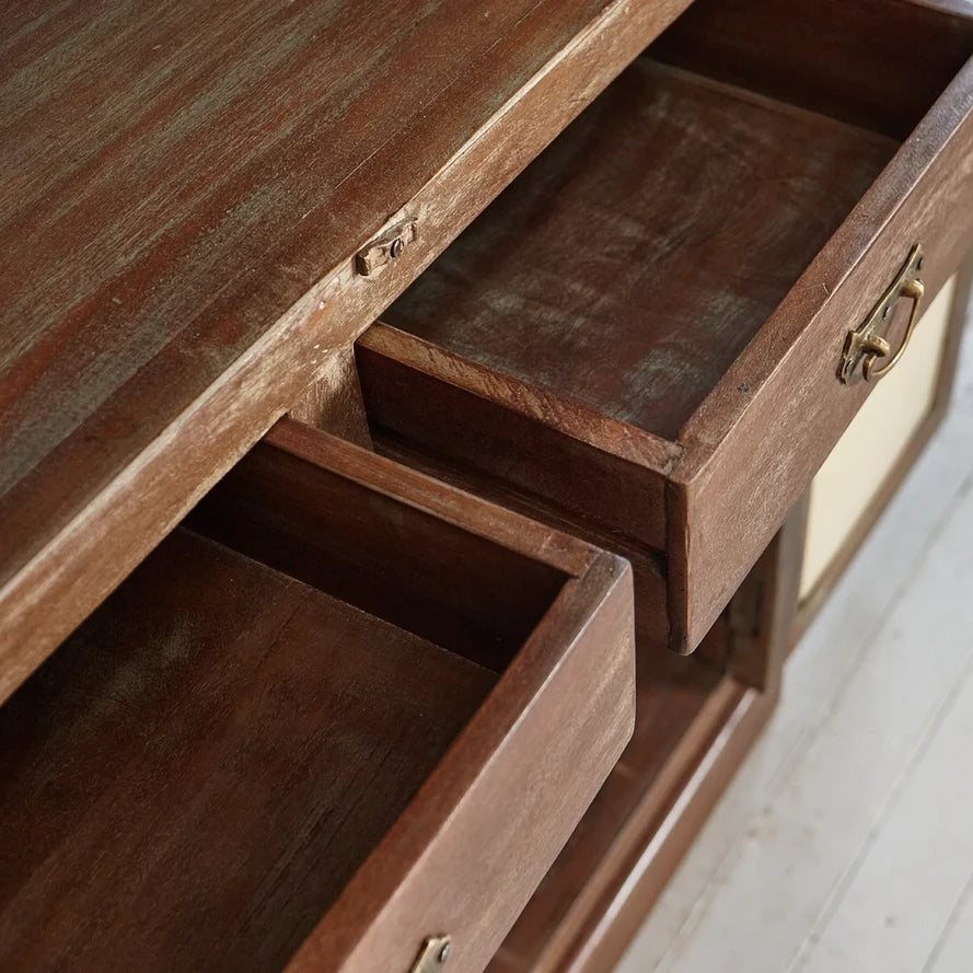 Wooden drawer with brass handles on a wooden cabinet.