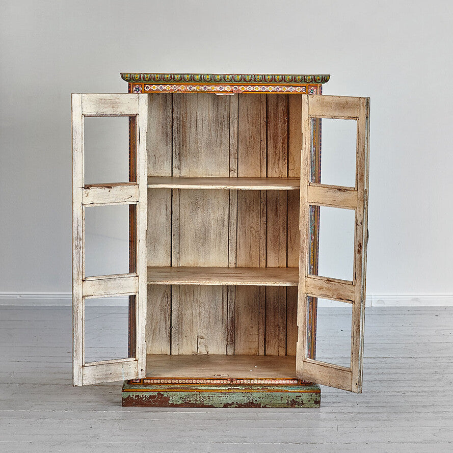 Wooden bookshelf with glass doors on a white floor and gray wall