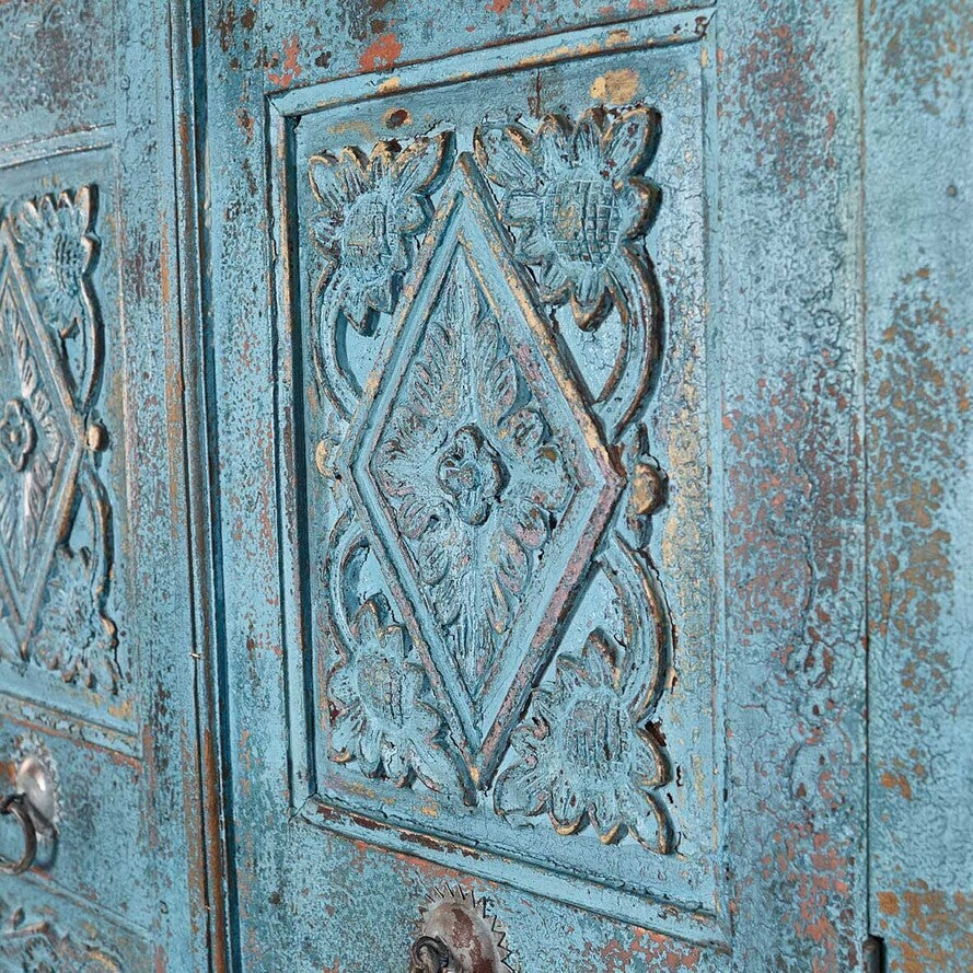 Decorative metal panel with intricate patterns on a textured blue surface