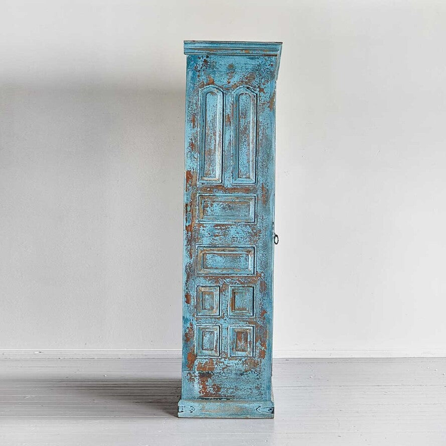 Tall, distressed blue wooden cabinet against a white background