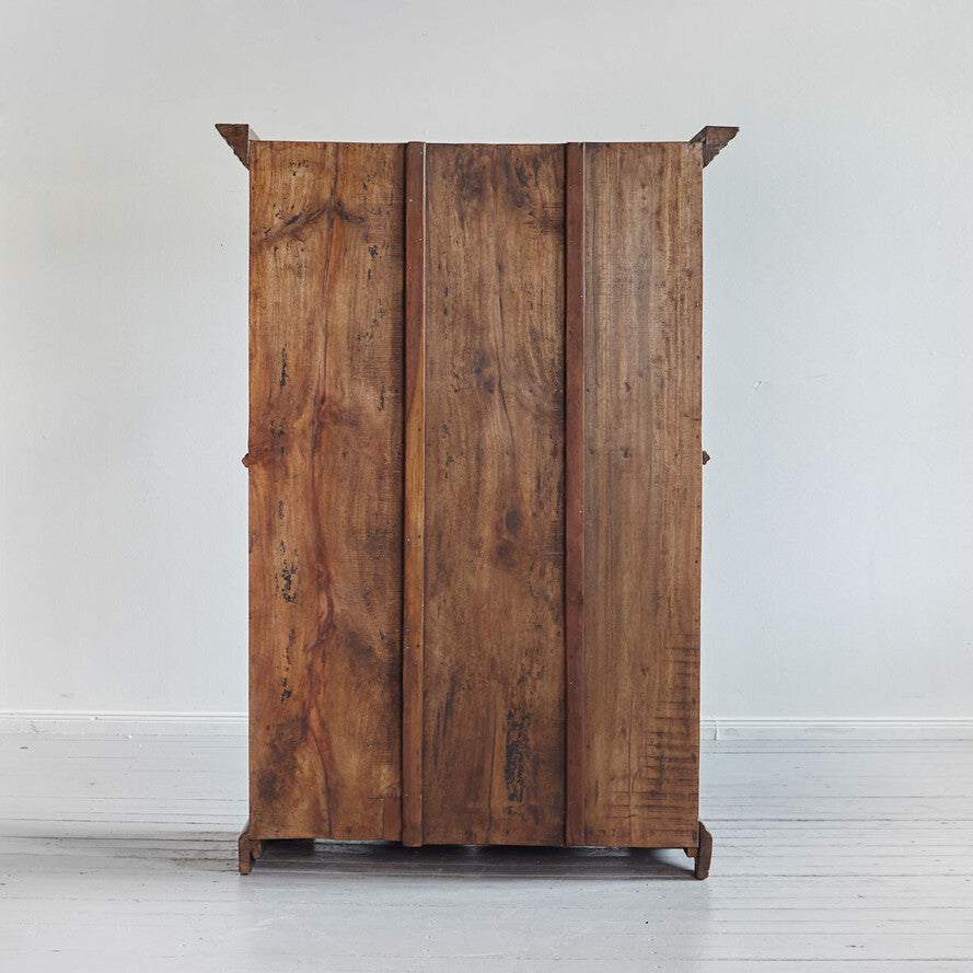 Wooden wardrobe with three doors on a white floor and light gray wall