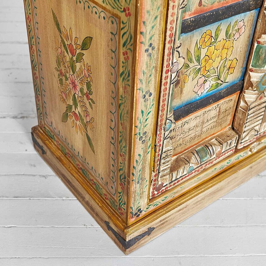 Decorative wooden box with floral patterns on a light wooden floor.