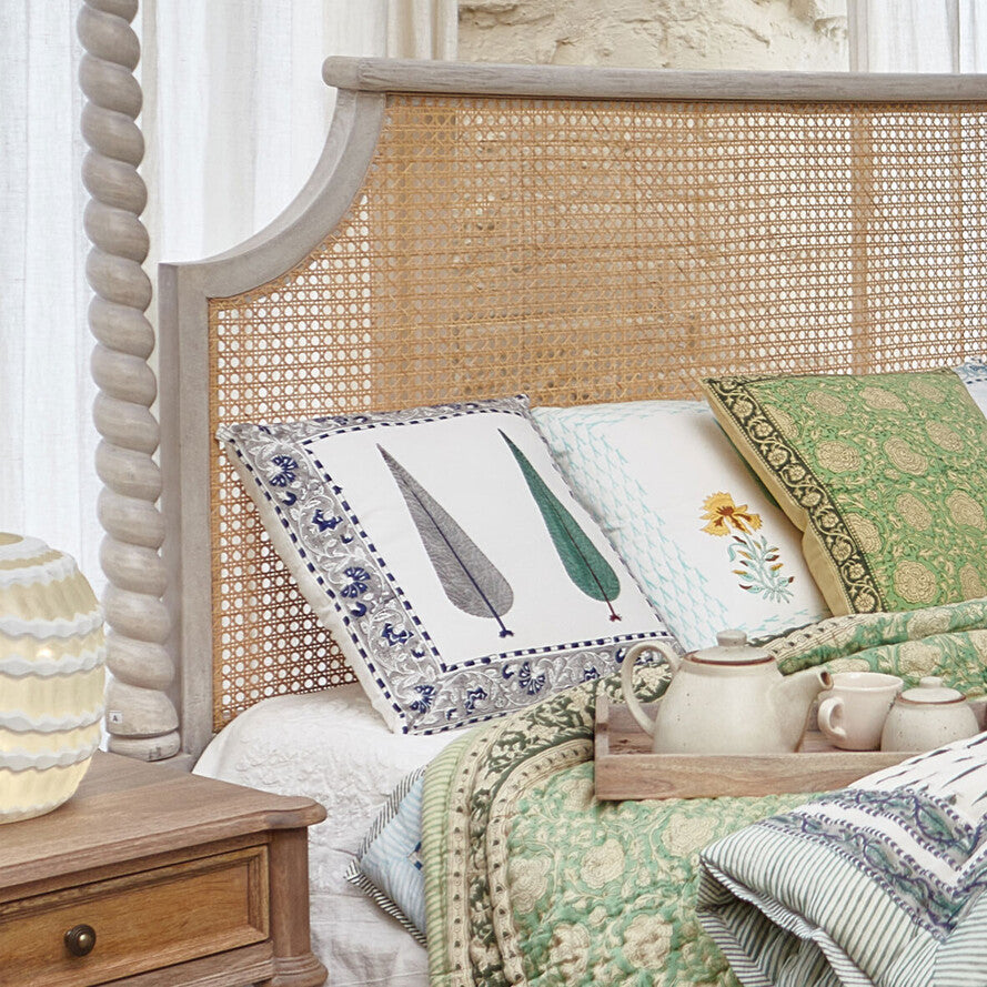 Bed with wicker headboard and decorative pillows in a bedroom setting