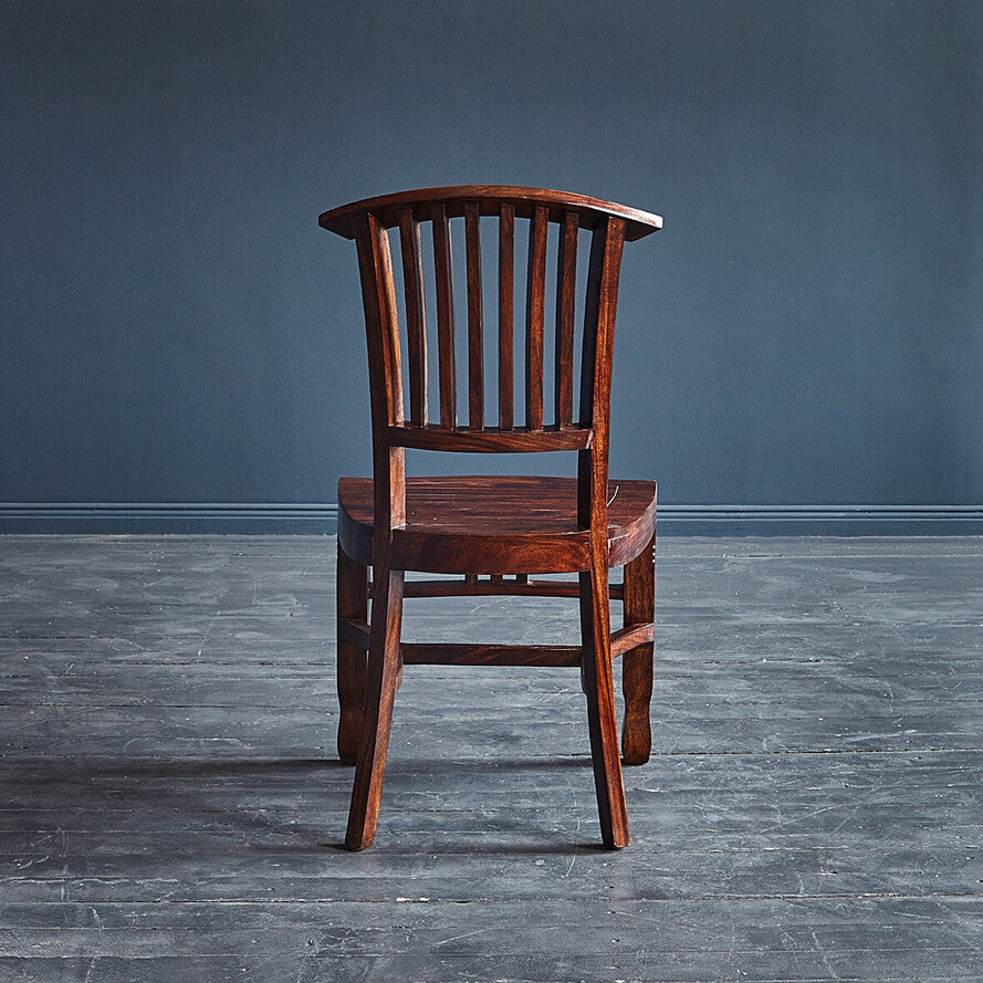 Wooden chair against a dark blue wall on a gray floor