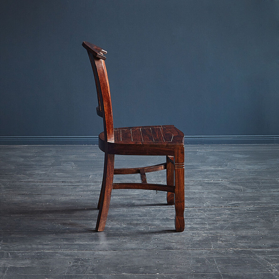 Wooden chair against a dark gray wall