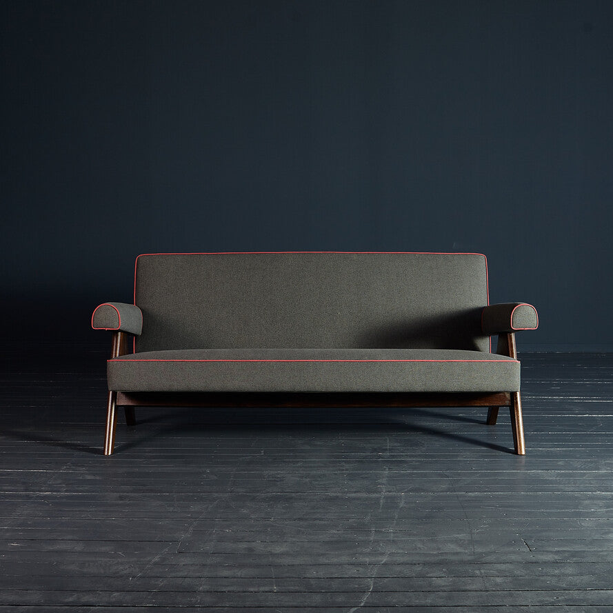 Gray sofa with red trim on a dark floor and background