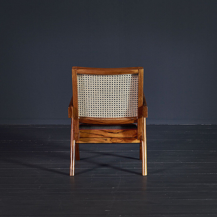 Wooden armchair with wicker backrest on a dark floor and background