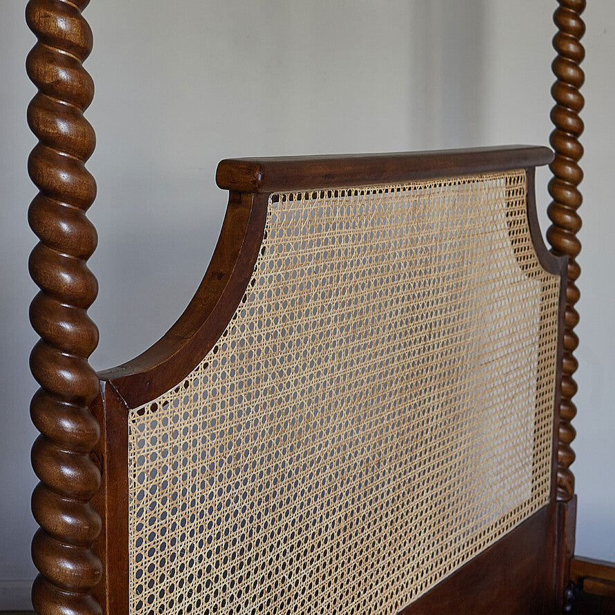 Close-up of a wooden chair with twisted backrest and woven seat.