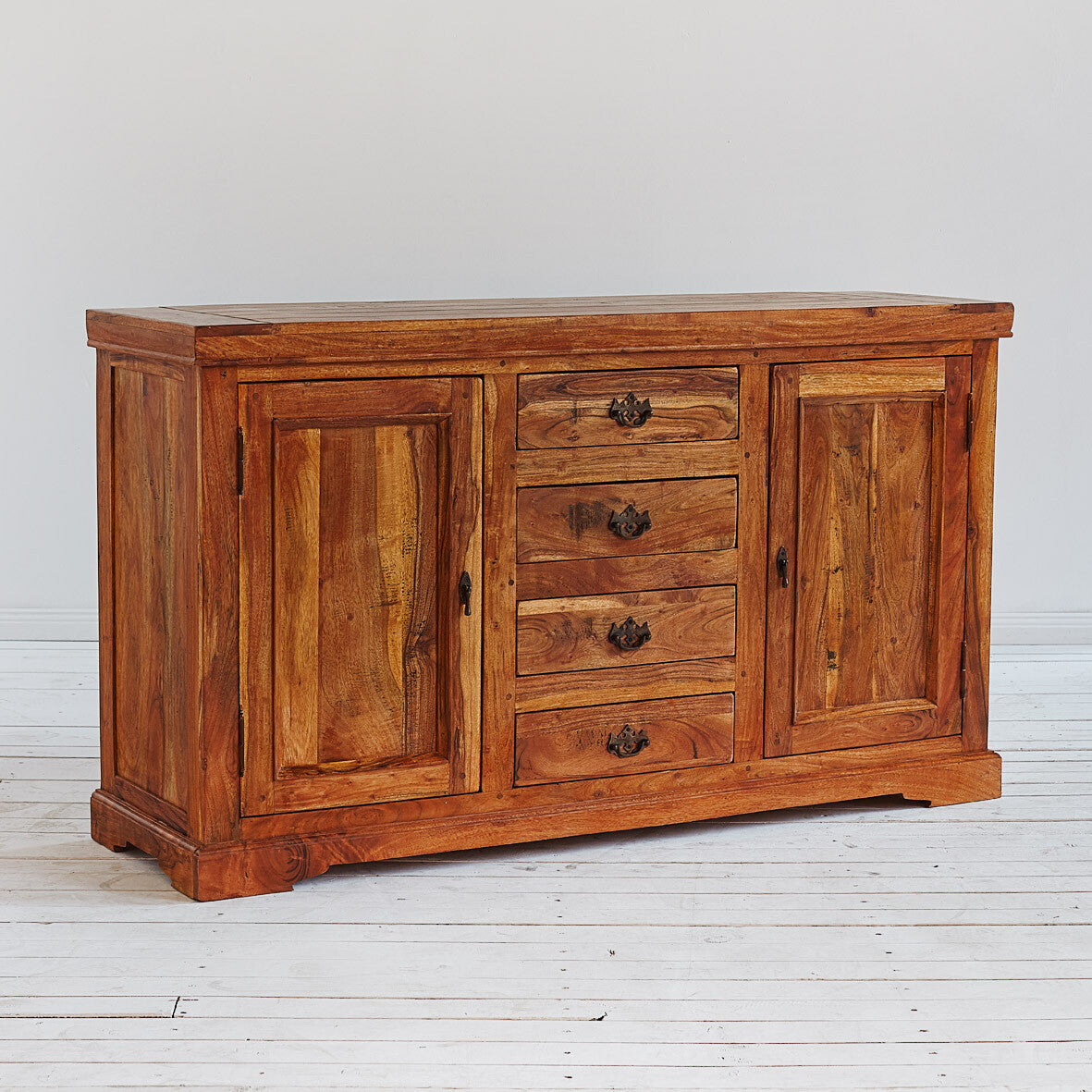 Wooden sideboard with drawers and doors on a light wooden floor.